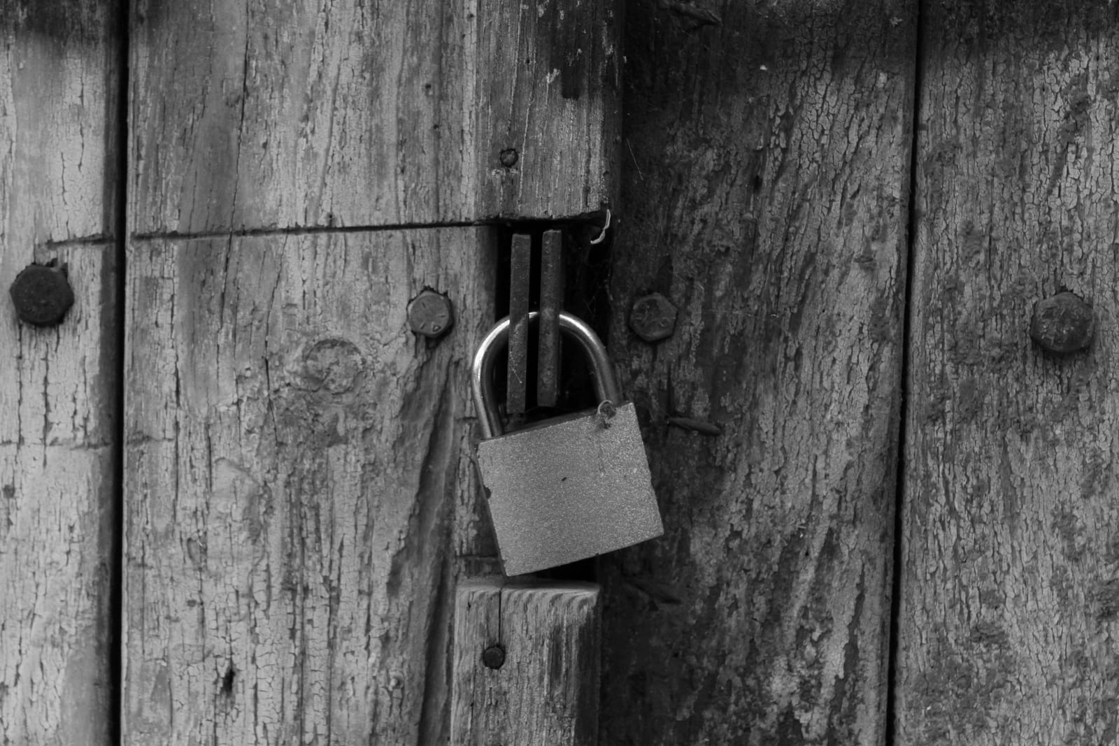 A metal padlock latched on a weathered wooden door