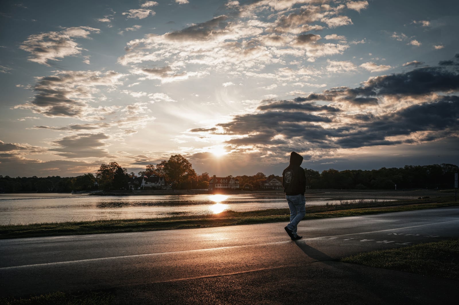 Person walking a lakeside road at sunset