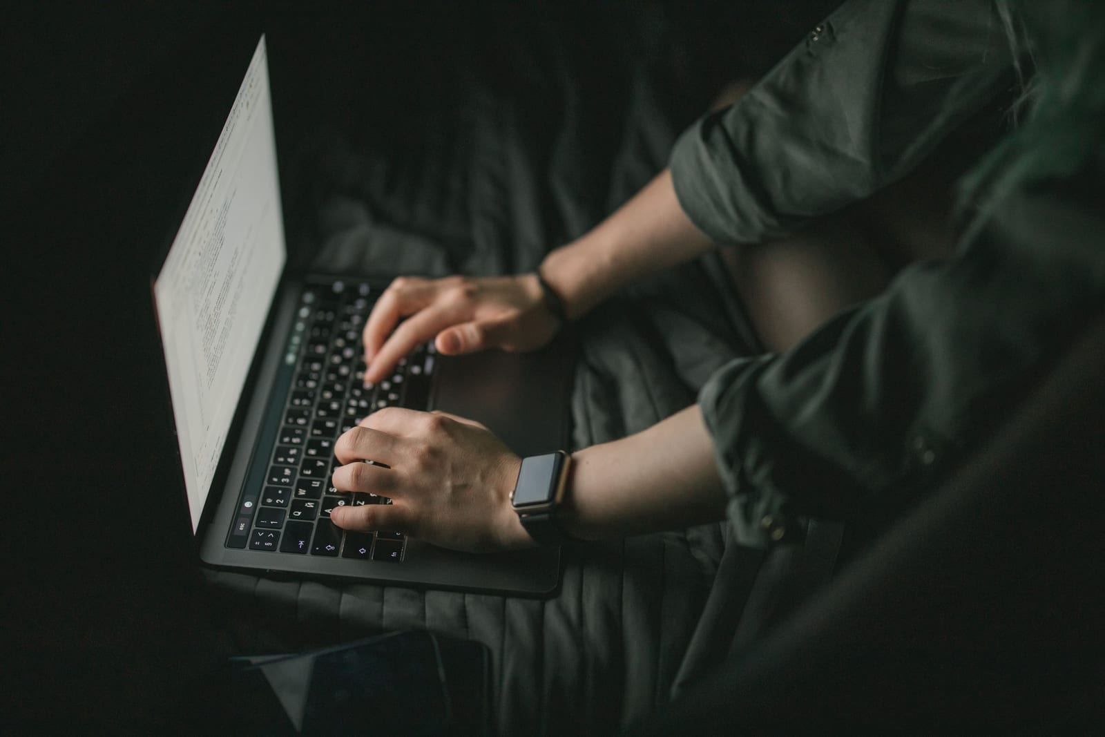 Clinician typing a report on a laptop late at night by lamplight