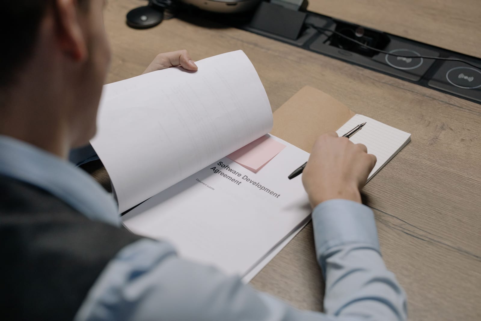 A professional reviewing a printed document and taking notes at a desk