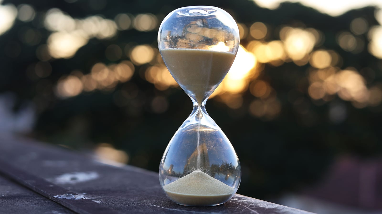 An hourglass with running sand against warm sunset light