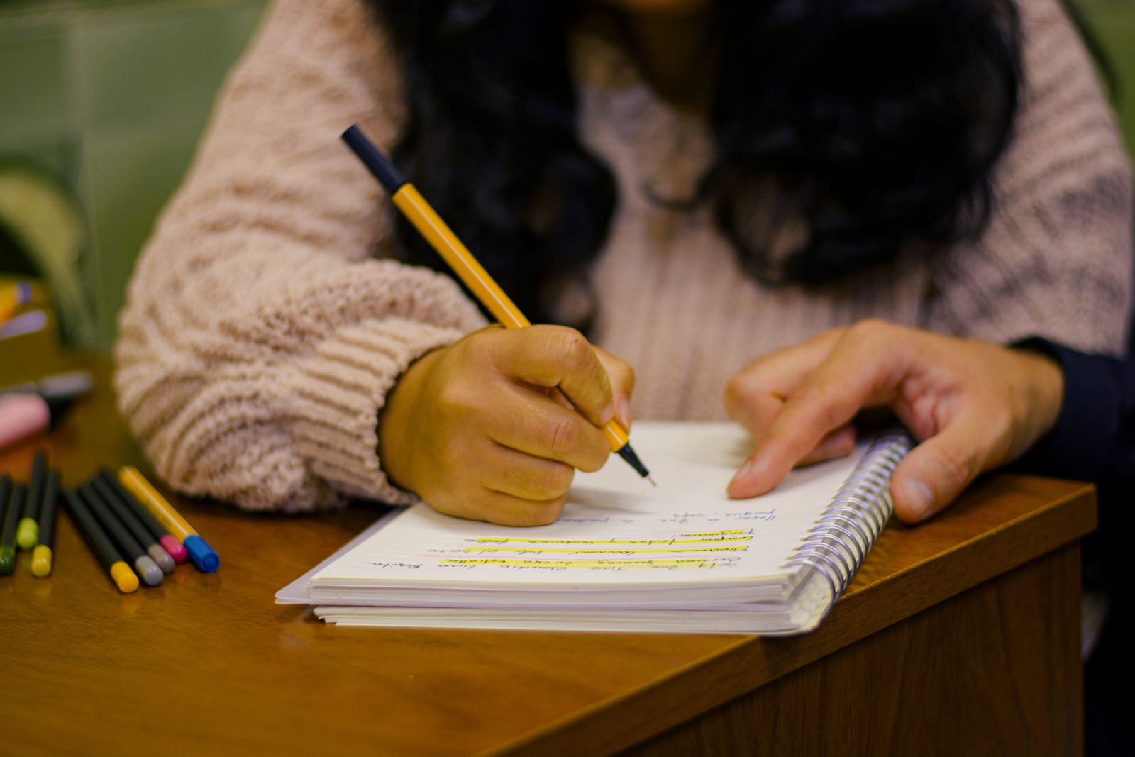 Writing in a spiral notebook at a desk