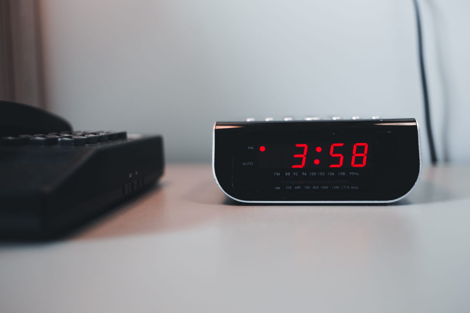 A digital clock glowing in the small hours on a desk at night