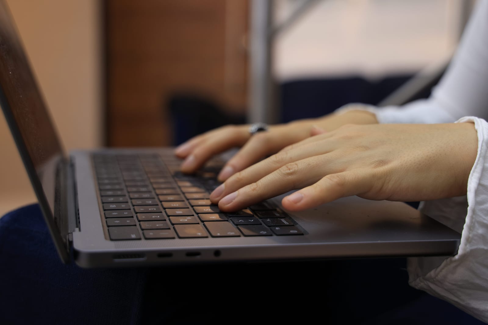 Hands typing a report on a laptop at a warm wooden desk