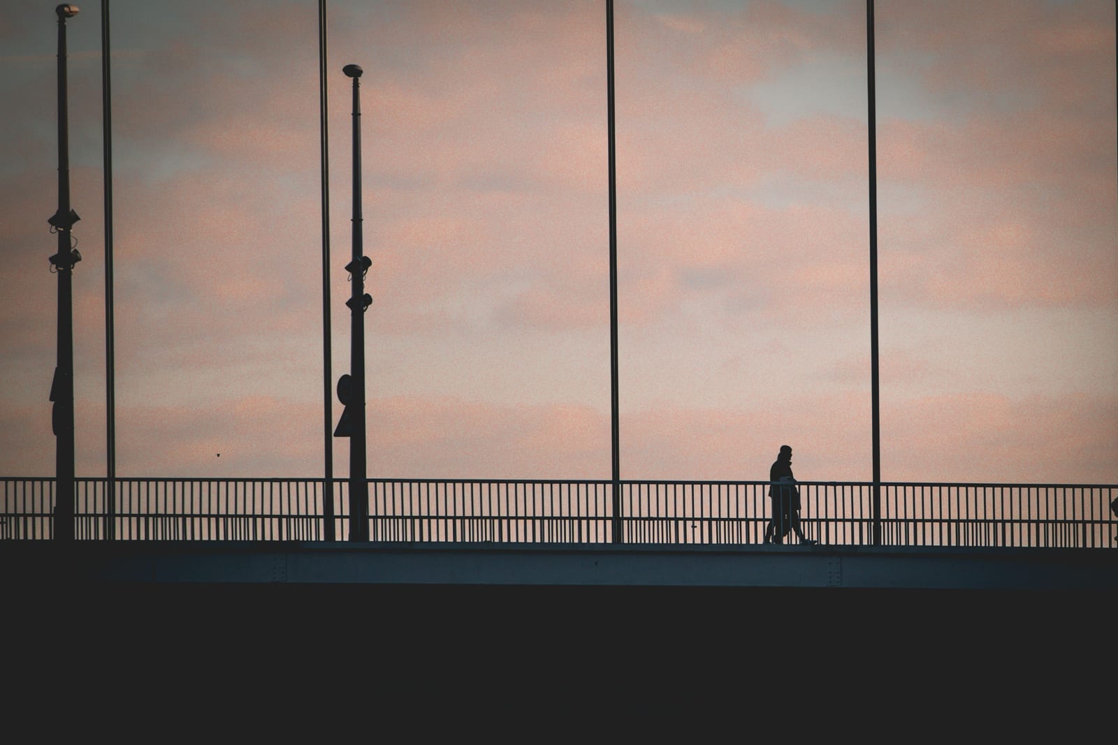 Figure crossing a bridge at dusk