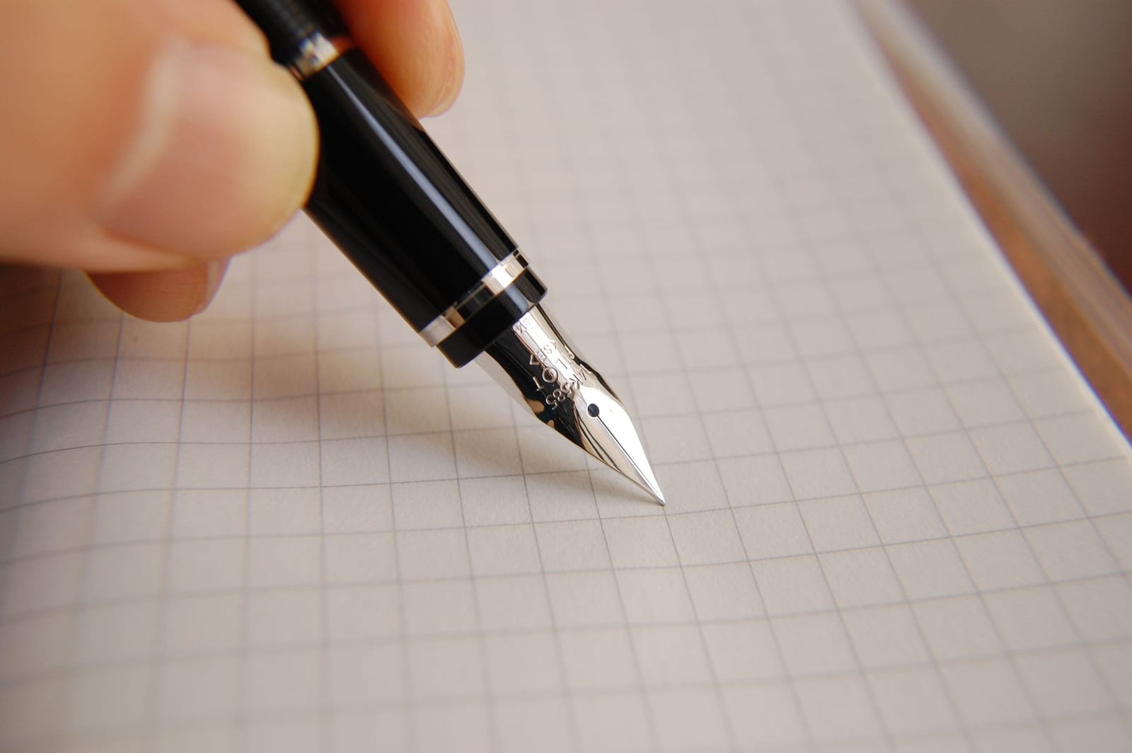 Macro of a fountain-pen nib resting on graph paper