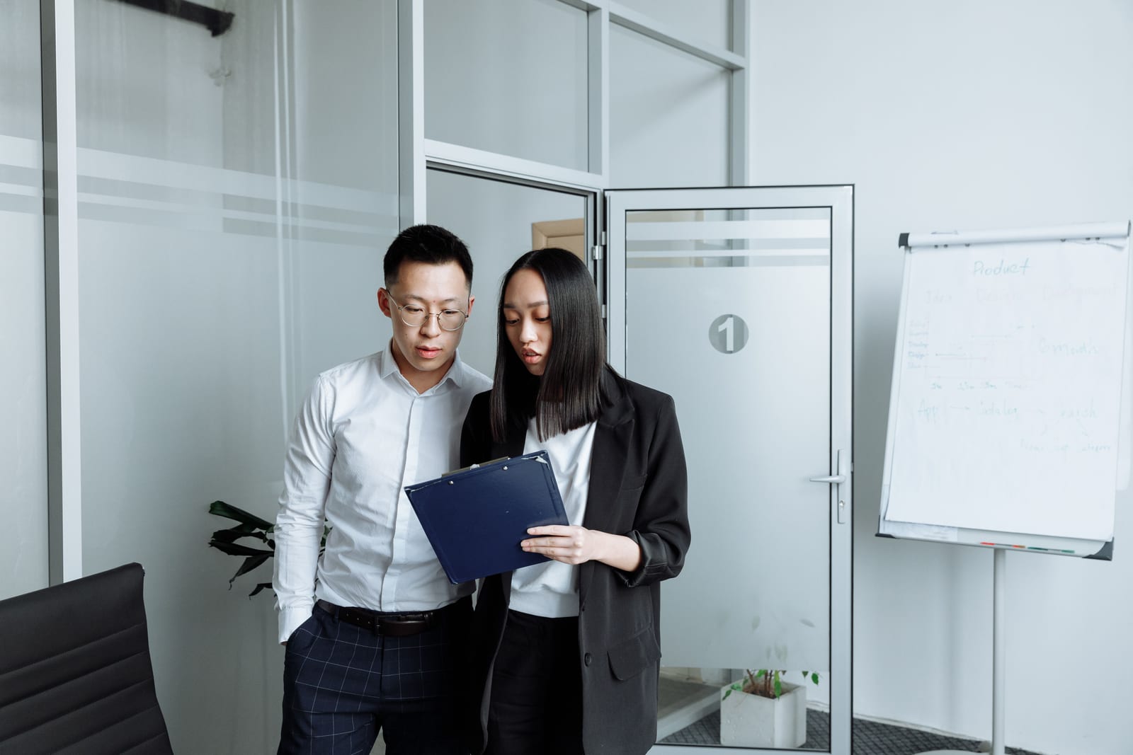Two professionals reviewing a clipboard together in a modern office